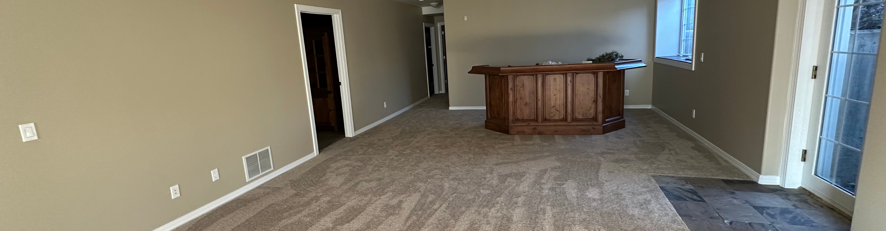 Living room with brown couch and two chairs, beige carpet